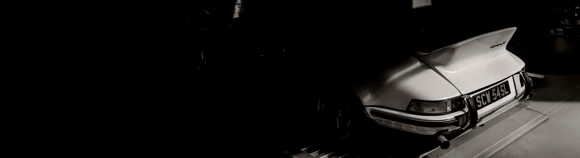 Classic Porsche 911 emerging from shadow, illustrating how restraint and presence can carry more meaning than visibility.