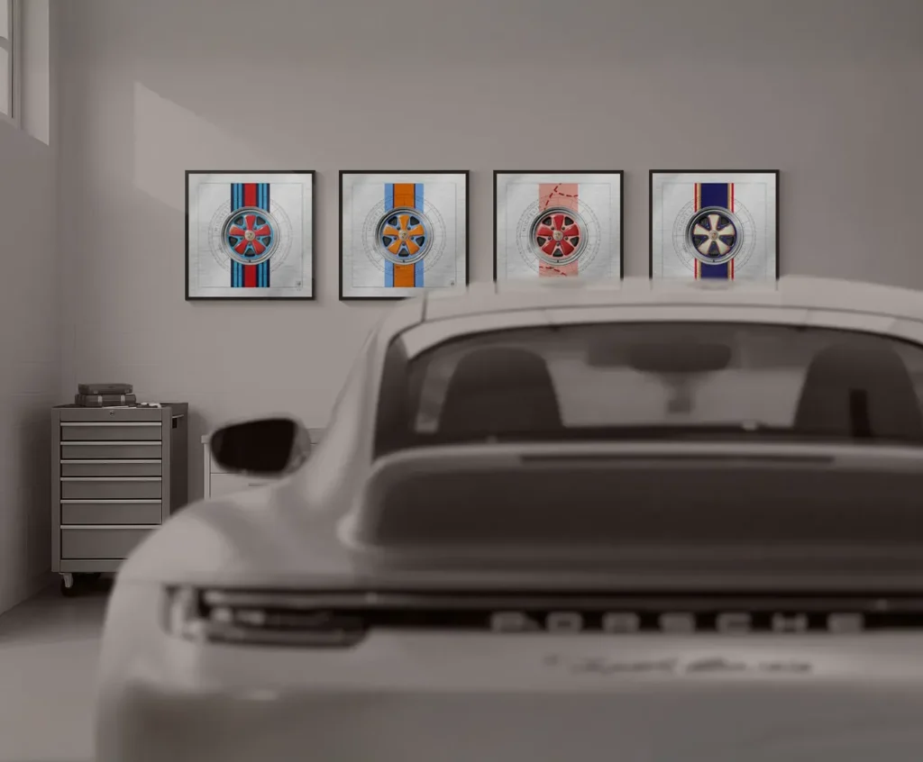 Modern Porsche 911 992 in a garage with THE 911 WAY Racing Fuchs collectible works displayed in the background.